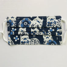 Load image into Gallery viewer, Made with three white cat designs on blue print 100% quilting cotton, this mask includes a filter pocket located in the pleats in the back of the mask for a filter of your choice, adjustable elastic ear loops and a bendable aluminum nose. Machine wash and dry after each use. 7” H x 7.5” W
