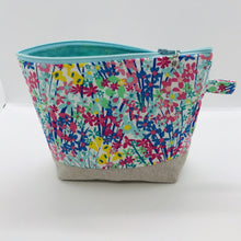 Load image into Gallery viewer, The pouch is made from 100% quilting cotton with a spring flower print, Kaufman Essex cotton/linen for the base, and a layer of fleece. The cute metal tassel gives an added touch. 7.5 W x 6”H x 2.5”D. Machine washable and dryer safe, or air dry.
