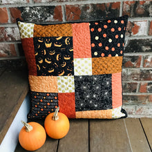 Load image into Gallery viewer, Scrappy Halloween pillow cover, 100% cotton in orange, black and gold prints. The pillow is quilted with a meandering design by machine with 40 wt Aurifil thread and has a hidden zipper in the back made of black Kona Cotton. The pillow cover only is offered and does not include the pillow form insert. The pillow insert needed is 18 x 18 inches. Machine wash with like colors in cold water with low suds soap such as Woolite, line dry.