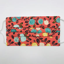 Load image into Gallery viewer, Made with three layers of flowers on orange print 100% quilting cotton, this mask includes a filter pocket located in the pleats in the back of the mask for a filter of your choice, adjustable elastic ear loops and a bendable aluminum nose. Machine wash and dry after each use. 7” H x 7.5” W