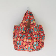 Load image into Gallery viewer, The tote is made of 100% quilting cotton featuring a green, yellow and white flowers on orange print and is fully lined. Machine washable and dryable or hang dry. Size: 17” x 21”.