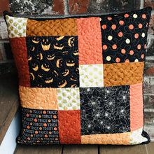 Load image into Gallery viewer, Scrappy Halloween pillow cover, 100% cotton in orange, black and gold prints. The pillow is quilted with a meandering design by machine with 40 wt Aurifil thread and has a hidden zipper in the back made of black Kona Cotton. The pillow cover only is offered and does not include the pillow form insert. The pillow insert needed is 18 x 18 inches. Machine wash with like colors in cold water with low suds soap such as Woolite, line dry.