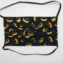 Load image into Gallery viewer, Made with three layers a spooky orange faces on black print 100% quilting cotton, this mask includes a filter pocket located in the pleats in the back of the mask for a filter of your choice, over the head elastic loops and a bendable aluminum nose. Machine wash and dry after each use. 7” H x 7.5” W