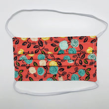 Load image into Gallery viewer, Made with three layers of flowers on orange print 100% quilting cotton, this mask includes a filter pocket located in the pleats in the back of the mask for a filter of your choice, elastic head bands and a bendable aluminum nose. Machine wash and dry after each use. 7” H x 7.5” W