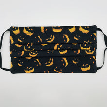 Load image into Gallery viewer, Made with three layers a spooky orange faces on black print 100% quilting cotton, this mask includes a filter pocket located in the pleats in the back of the mask for a filter of your choice, adjustable elastic ear loops and a bendable aluminum nose. Machine wash and dry after each use. 7” H x 7.5” W