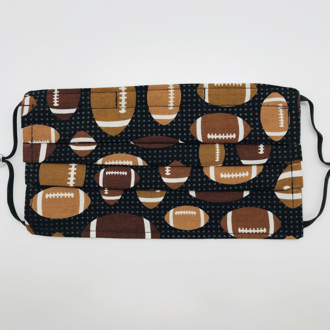 Made with three layers of footballs on black print 100% quilting cotton, this mask includes a filter pocket located in the pleats in the back of the mask for a filter of your choice, adjustable elastic ear loops and a bendable aluminum nose. Machine wash and dry after each use. 7” H x 7.5” W