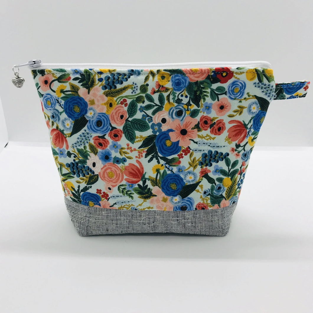 The pouch is made from 100% quilting cotton by Rifle Paper Co and features a multicolored woodland floral print, Kaufman Essex cotton/linen for the base, and a layer of fleece. The cute metal tassel gives an added touch. 7.5 W x 6”H x 2.5”D. Machine washable and dryer safe, or air dry.