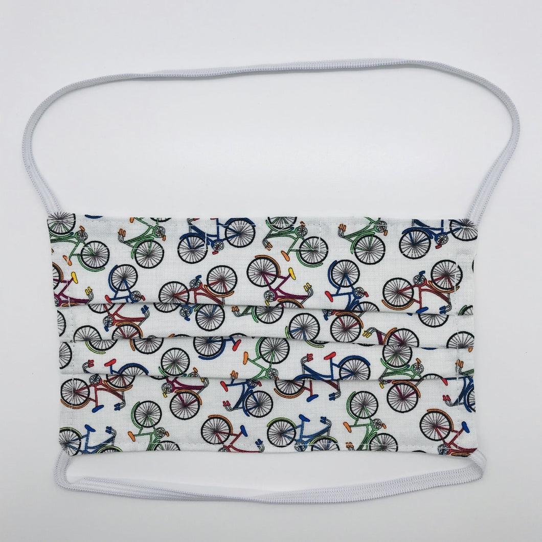 Masks are made of 100% quilting-weight cotton featuring multi colored bikes on a white background.  This mask has elastic bands and a bendable nose piece. Wash in washing machine and dry in dryer after each use. 7” H x 7.5” W