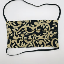 Load image into Gallery viewer, Masks are made of 2 layers 100% quilting cotton featuring a gold swirls on black print, over the head elastic loops and a bendable aluminum nose. Wash in washing machine and dry in dryer after each use. 7” H x 7.5” W.  
