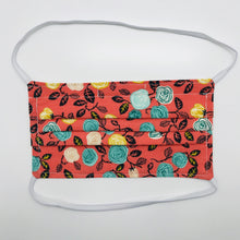 Load image into Gallery viewer, Masks are made of 2 layers of flowers on orange print 100% quilting cotton and have behind the head elastic bands. The masks also have a bendable aluminum nose. Wash in washing machine and dry in dryer after each use. 7” H x 7.5” W
