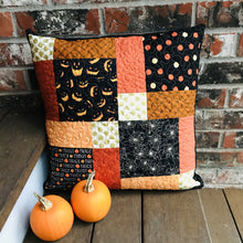 Load image into Gallery viewer, Scrappy Halloween pillow cover, 100% cotton in orange, black and gold prints. The pillow is quilted with a meandering design by machine with 40 wt Aurifil thread and has a hidden zipper in the back made of black Kona Cotton. The pillow cover only is offered and does not include the pillow form insert. The pillow insert needed is 18 x 18 inches. Machine wash with like colors in cold water with low suds soap such as Woolite, line dry.
