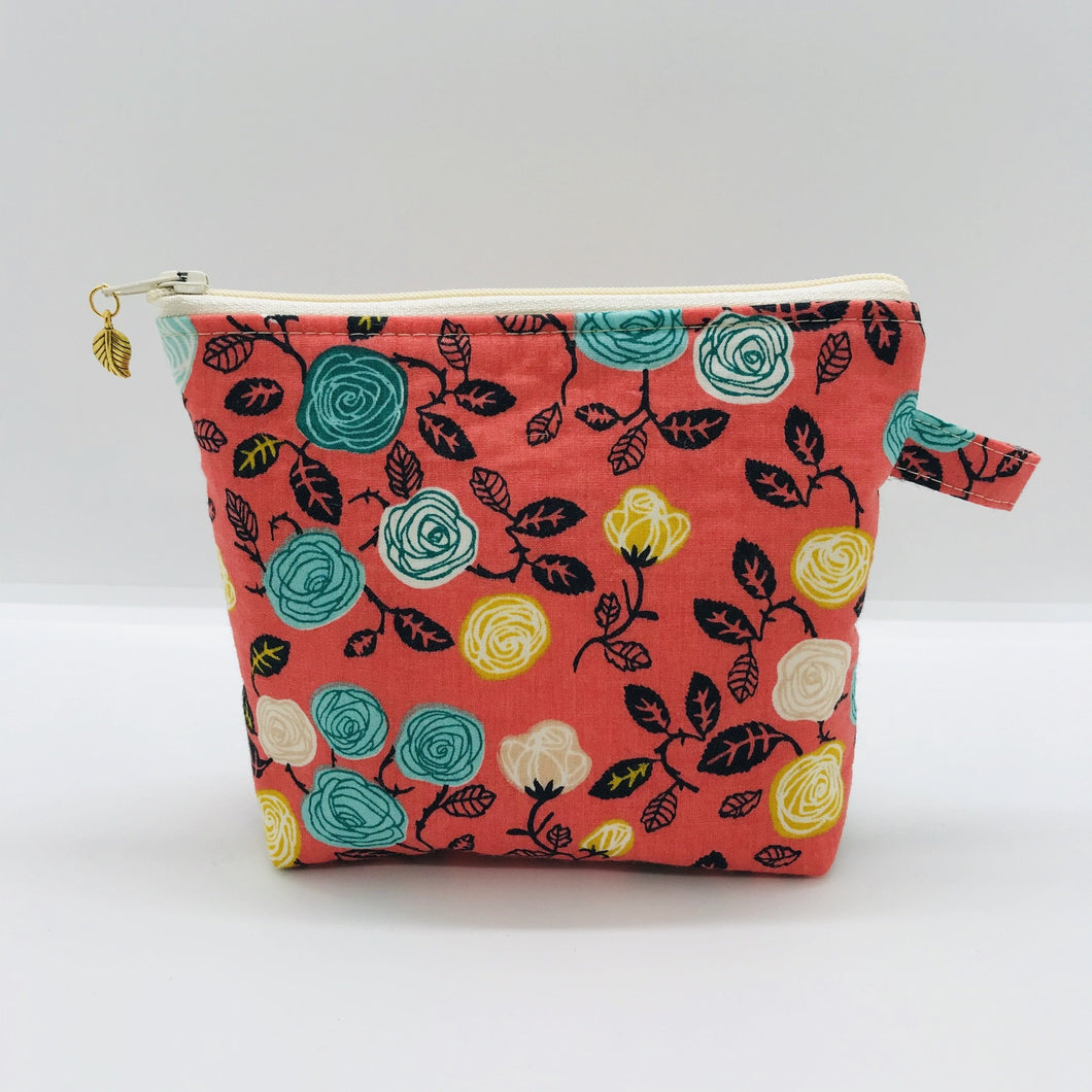 The pouch is made from 100% cotton flowers on orange print and has a layer of fleece for structure and a cute metal tassel. The pouch design is from the Becca Bags pattern from Lazy Girl Design.  6”W x 4.5” H x 1”D. Machine washable and dryer safe or air dry.