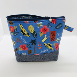 The pouch is made from 100% quilting cotton with a blue travel themed print, Kaufman Essex cotton/linen for the base, and a layer of fleece. The cute metal tassel gives an added touch. 7.5 W x 6”H x 2.5”D. Machine washable and dryer safe, or air dry.
