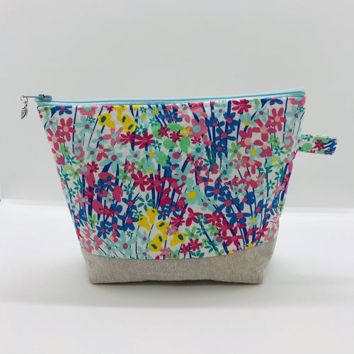 The pouch is made from 100% quilting cotton with a spring flower print, Kaufman Essex cotton/linen for the base, and a layer of fleece. The cute metal tassel gives an added touch.  7.5 W x 6”H x 2.5”D. Machine washable and dryer safe, or air dry.