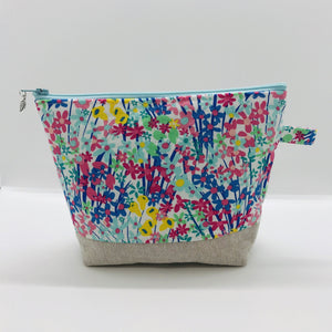 The pouch is made from 100% quilting cotton with a spring flower print, Kaufman Essex cotton/linen for the base, and a layer of fleece. The cute metal tassel gives an added touch.  7.5 W x 6”H x 2.5”D. Machine washable and dryer safe, or air dry.