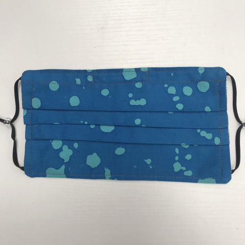 100% quilting-weight batik cotton blue splatter design face mask with adjustable elastic ear loops and bendable nose piece. Washable, reusable fabric face mask. Wash in washing machine and dry in dryer after each use. 7” H x 7.5” W  Fabric from the Handcrafted Batiks collection by Alison Glass from Andover Fabrics. 