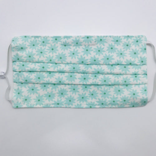 Made with three layers aqua flowers on white print 100% quilting cotton, this mask includes a filter pocket located in the pleats in the back of the mask for a filter of your choice, adjustable elastic ear loops and a bendable aluminum nose. Machine wash and dry after each use. 7” H x 7.5” W