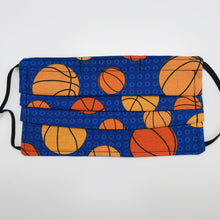 Load image into Gallery viewer, Made with three layers of basketballs on blue print 100% quilting cotton, this mask includes a filter pocket located in the pleats in the back of the mask for a filter of your choice, adjustable elastic ear loops and a bendable aluminum nose. Machine wash and dry after each use. 7” H x 7.5” W
