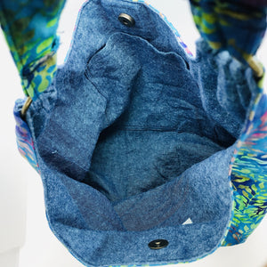 This beautiful 100% green, blue and purple cotton batik makesa great slouch bag that is light and durable. The lining is beautiful Essex cotton\linen from Robert Kaufman and has a magnetic snap and inner pocket. 15.5” W & 14”H. Total length with strap 33”