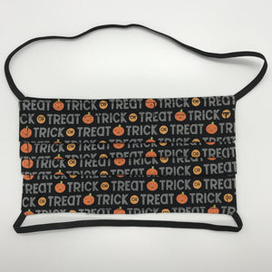Made with three layers of trick or treat words and orange pumpkins on black print 100% quilting cotton, this mask includes a filter pocket located in the pleats in the back of the mask for a filter of your choice, over the head elastic loops and a bendable aluminum nose. Machine wash and dry after each use. 7” H x 7.5” W