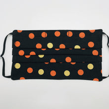 Load image into Gallery viewer, Made with three layers of orange and gold dots on black print 100% quilting cotton, this mask includes a filter pocket located in the pleats in the back of the mask for a filter of your choice, adjustable elastic ear loops and a bendable aluminum nose. Machine wash and dry after each use. 7” H x 7.5” W
