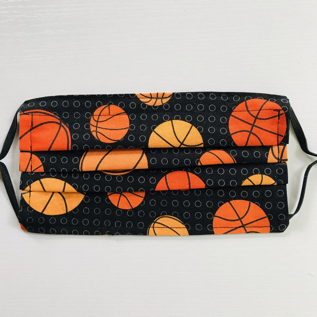 100% quilting-weight sports themed print cotton face mask with adjustable elastic ear loops and bendable nose piece. Washable, reusable fabric face mask. Wash in washing machine and dry in dryer after each use. 7” H x 7.5” W  These tossed basketballs on black are from the fabric collection: Sports Life by Robert Kaufman Fabrics
