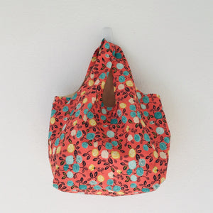 The tote is made of 100% quilting cotton featuring  a green, yellow and white flowers on orange print and is fully lined. Machine washable and dryable or hang dry.  Size: 17” x 21”. 