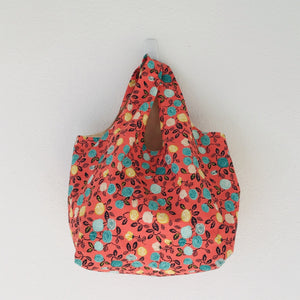 The tote is made of 100% quilting cotton featuring  a green, yellow and white flowers on orange print and is fully lined. Machine washable and dryable or hang dry.  Size: 17” x 21”. 