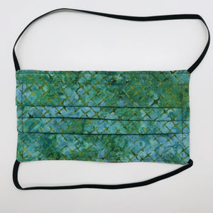 Made with three layers of blue and green batik 100% quilting cotton, this mask includes a filter pocket located in the pleats in the back of the mask for a filter of your choice, elastic head bands and a bendable aluminum nose. Machine wash and dry after each use. 7” H x 7.5” W