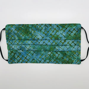 Made with three layers blue and green batik 100% quilting cotton, this mask includes a filter pocket located in the pleats in the back of the mask for a filter of your choice, adjustable elastic ear loops and a bendable aluminum nose. Machine wash and dry after each use. 7” H x 7.5” W