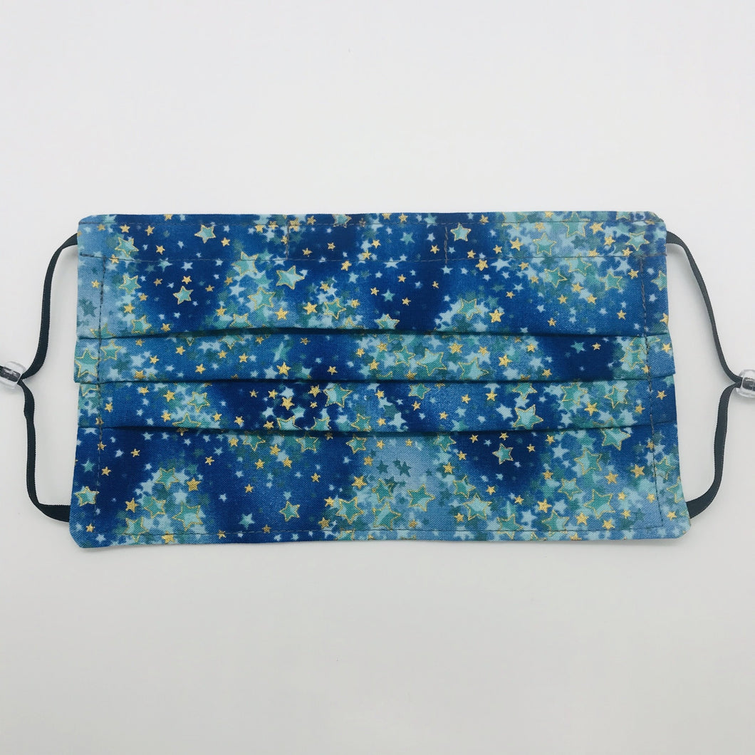 The masks are made of 100% quilting-weight cotton featuring a blue and green with gold stars print. The masks have adjustable elastic ear loops and a bendable nose piece. Machine wash and dry after each use. 7” H x 7.5” W
