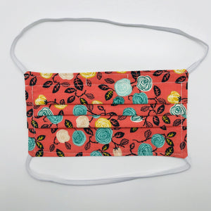 Made with three layers of flowers on orange print 100% quilting cotton, this mask includes a filter pocket located in the pleats in the back of the mask for a filter of your choice, elastic head bands and a bendable aluminum nose. Machine wash and dry after each use. 7” H x 7.5” W