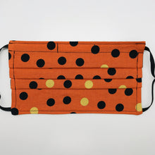 Load image into Gallery viewer, Made with three layers of orange and gold dots on black print 100% quilting cotton, this mask includes a filter pocket located in the pleats in the back of the mask for a filter of your choice, adjustable elastic ear loops and a bendable aluminum nose. Machine wash and dry after each use. 7” H x 7.5” W

