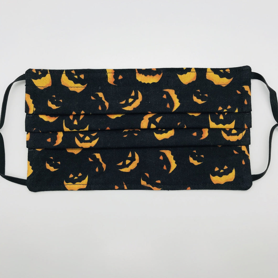Made with three layers a spooky orange faces on black print 100% quilting cotton, this mask includes a filter pocket located in the pleats in the back of the mask for a filter of your choice, adjustable elastic ear loops and a bendable aluminum nose. Machine wash and dry after each use. 7” H x 7.5” W