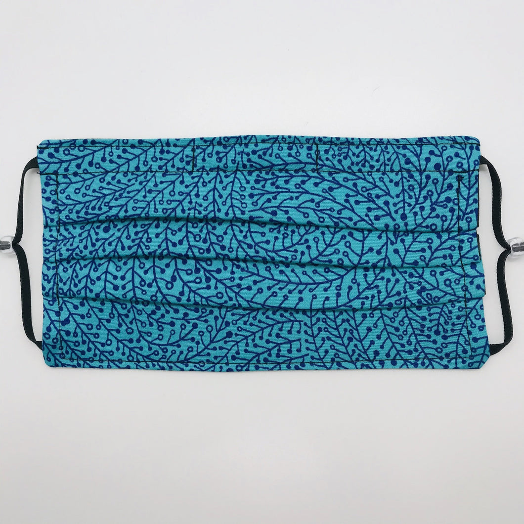 Masks are made of 2 layers of 100% quilting-weight blue/teal swirl print cotton fabric. The mask has elastic adjustable ear loops and a bendable aluminum nose piece. Machine wash and dry after each use. 7” H x 7.5” W