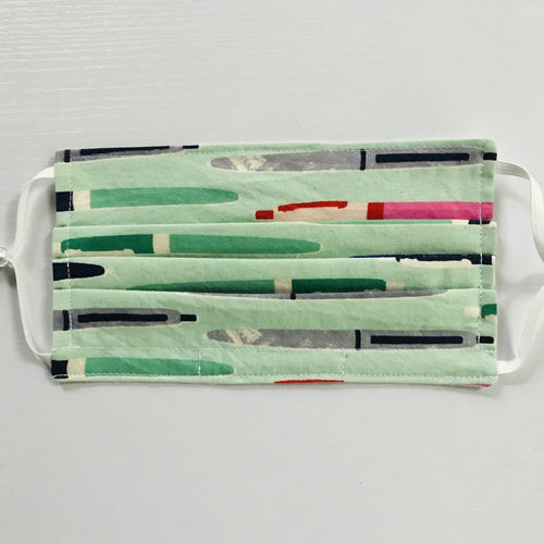 Made with three layers green, grey and pink pens on green print 100% quilting cotton, this mask includes a filter pocket located in the pleats in the back of the mask for a filter of your choice, adjustable elastic ear loops and a bendable aluminum nose. Machine wash and dry after each use. 7” H x 7.5” W