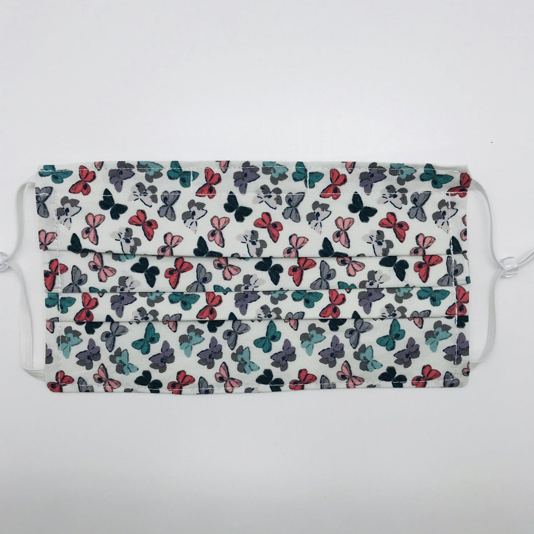 Made with three layers of 100% quilting-weigh cotton and features a butterfly print. This mask includes a filter pocket located in the pleats in the back of the mask for a filter of your choice. This mask has adjustable elastic ear loops and also has a bendable aluminum nose piece.  Machine wash and dry after each use. 7” H x 7.5” W